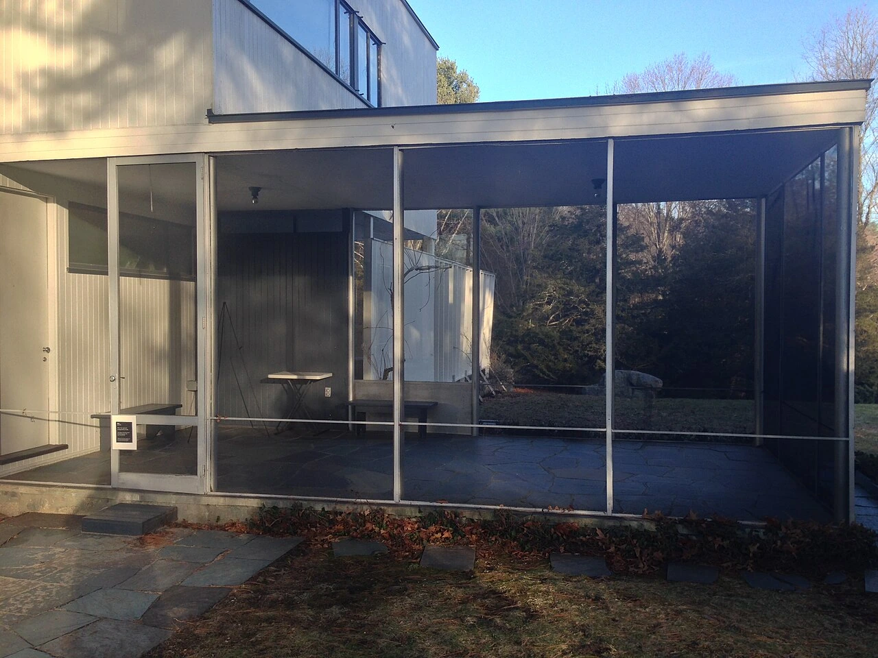 A screened patio enclosure attached to a house, shown in a landscape photo.