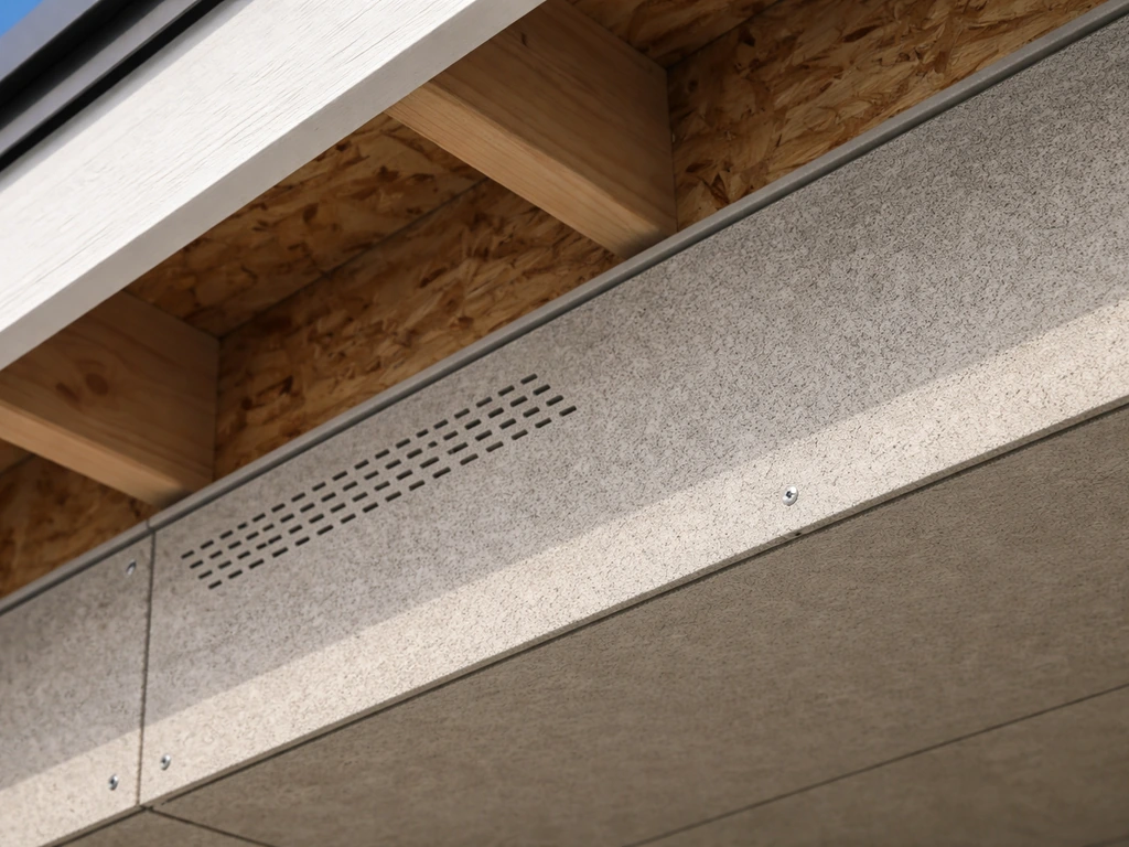 Close-up of installed fiber cement soffit panel with visible vented section under roof deck.